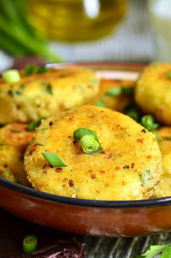 Homemade potato patties with herbs and green onion on rustic background.